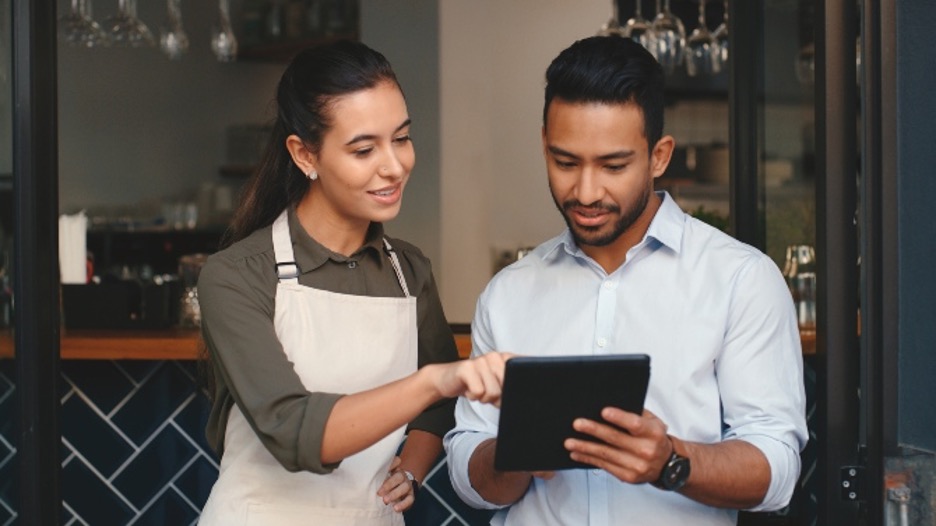 A merchant services sales agent discusses payment solutions and ISV integration with a shop owner in front of her store.